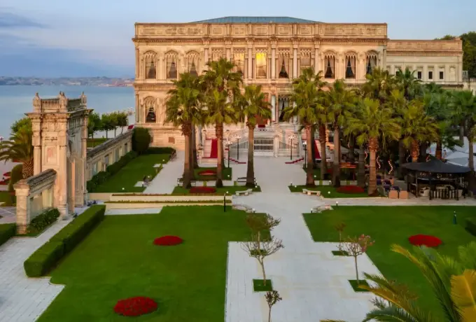 The garden and waterfront facade of a Bosphorus palace in Istanbul, lined with palms.