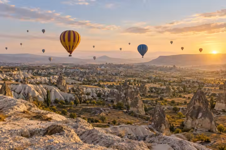 Gold and burgundy hot air balloon above Cappadocia’s fairy chimneys at dawn
