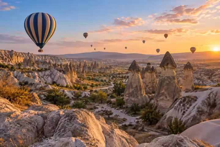 Blue and cream hot air balloon above Cappadocia’s capped fairy chimneys at dawn