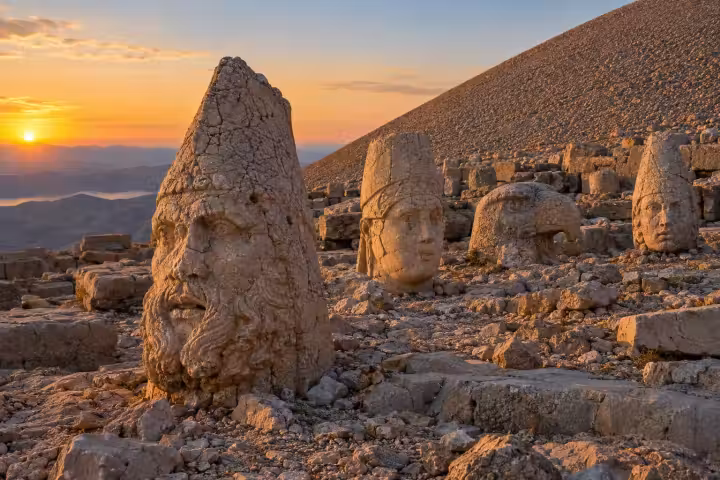 Ancient stone heads beside Mount Nemrut’s summit mound in golden dawn light