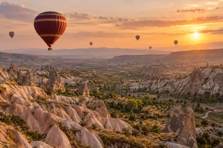 Burgundy and gold hot air balloon above Cappadocia’s valleys in sunrise light