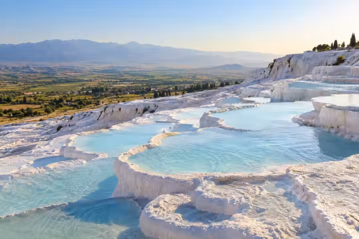 Pale blue pools and white travertine terraces overlooking the valley at Pamukkale
