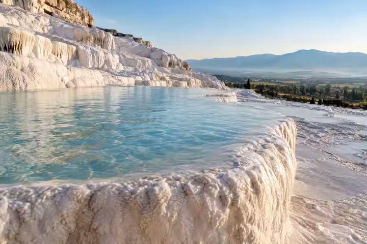 Morning light on a turquoise pool and white travertine edge at Pamukkale