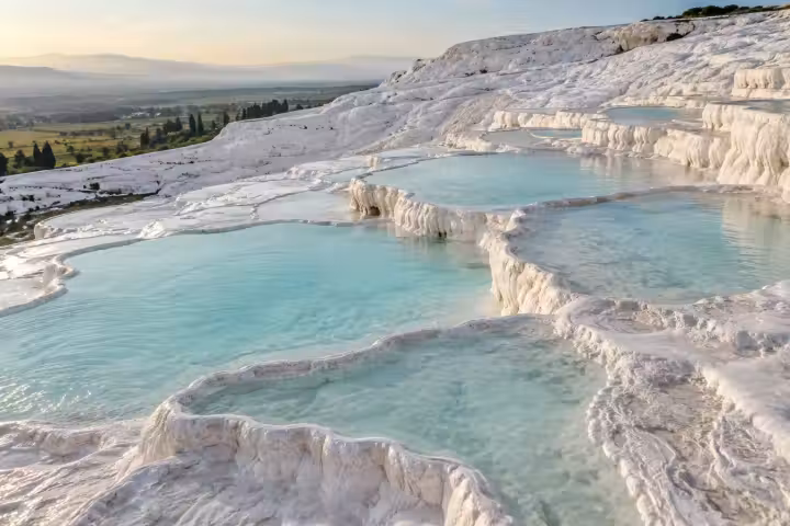 Shallow blue pools and scalloped white travertine terraces at Pamukkale in morning light