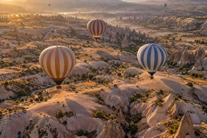Hot air balloons casting long shadows across Cappadocia’s valleys at sunrise