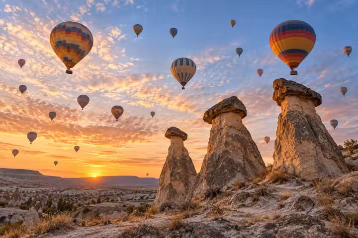 Hot air balloons across a glowing dawn sky above Cappadocia fairy chimneys