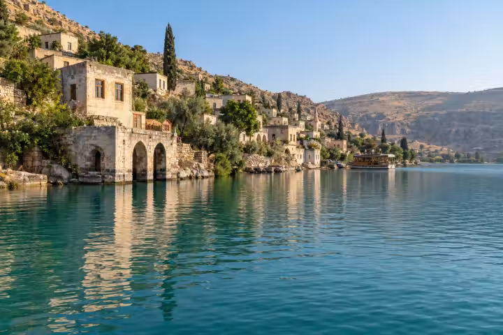 Stone houses and a small boat along the Euphrates reservoir waterfront at Halfeti