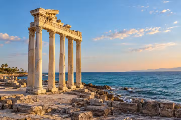 Temple of Apollo columns beside the blue Mediterranean Sea in Side, lit by warm afternoon sunlight