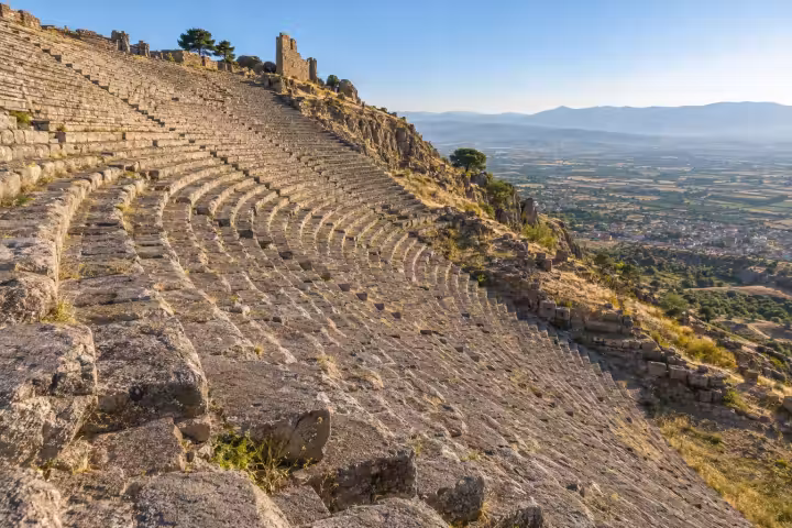 Steep curved stone seating of Pergamon’s ancient theatre overlooking the Bergama plain in warm morning light