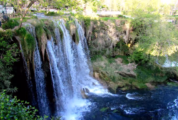 Several drops breaking over mossy shelves into churning water inside the Antalya park