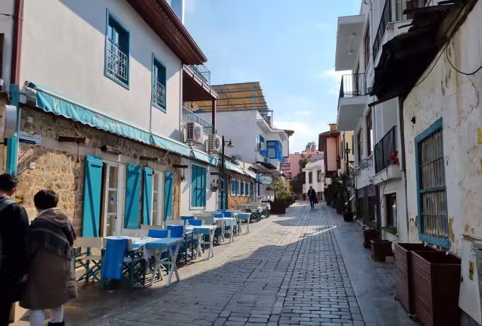Whitewash and teal shutters down a setted Kaleici lane, tables out in the winter sun