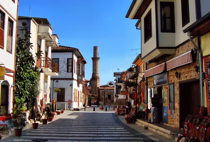 Cut-off Kesik shaft closing a marble-paved Kaleici lane hung with rugs outside a carpet shop