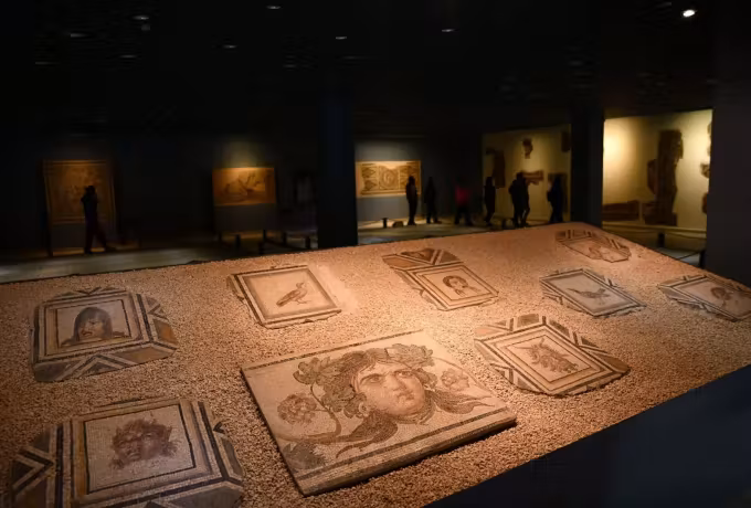 Dim main room of the Zeugma museum with wide Roman pavements set out across the floor