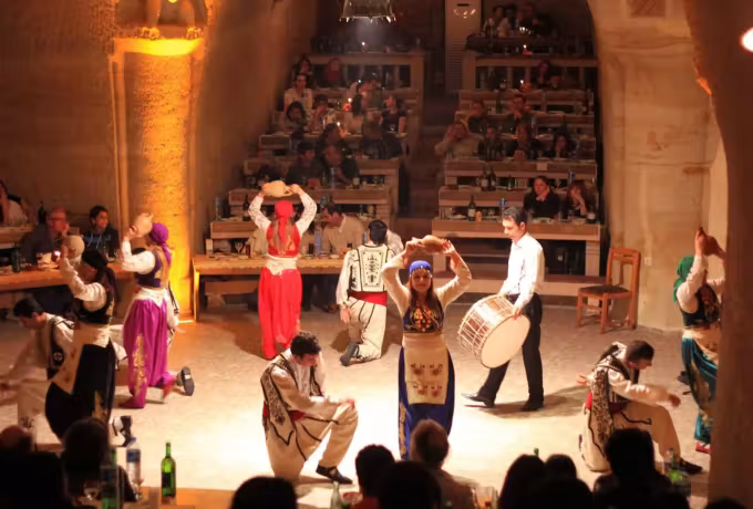 Dancing circles a standing drum in a hewn Cappadocia dining hall as guests look on