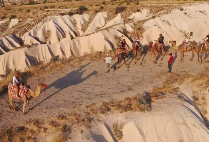 Low sun drawing shadows over corrugated ground as a mounted train works across it, Cappadocia