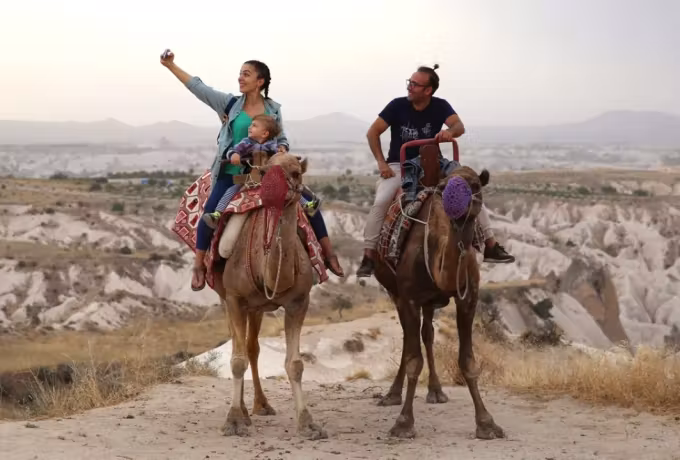 Pair stopped high up, one arm out to show the bleached country dropping away in front, Cappadocia