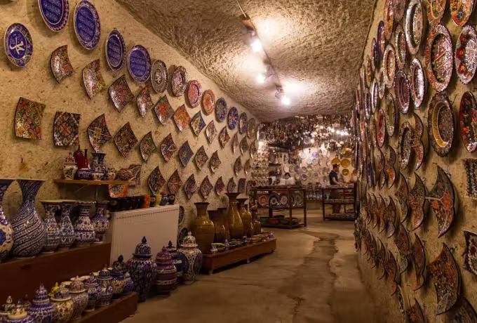Decorated dishes covering every wall of a long barrel-roofed showroom, jugs racked beneath, Cappadocia
