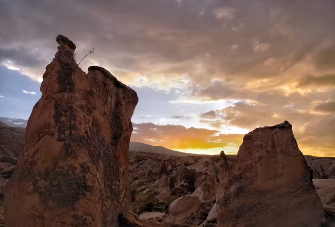 Dark silhouettes of eroded rock under a broad, heavily clouded end to the day, Cappadocia