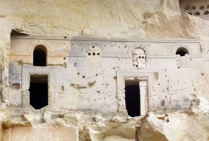 Pale front of the Cavusin rock church with arched openings cut into the cliff