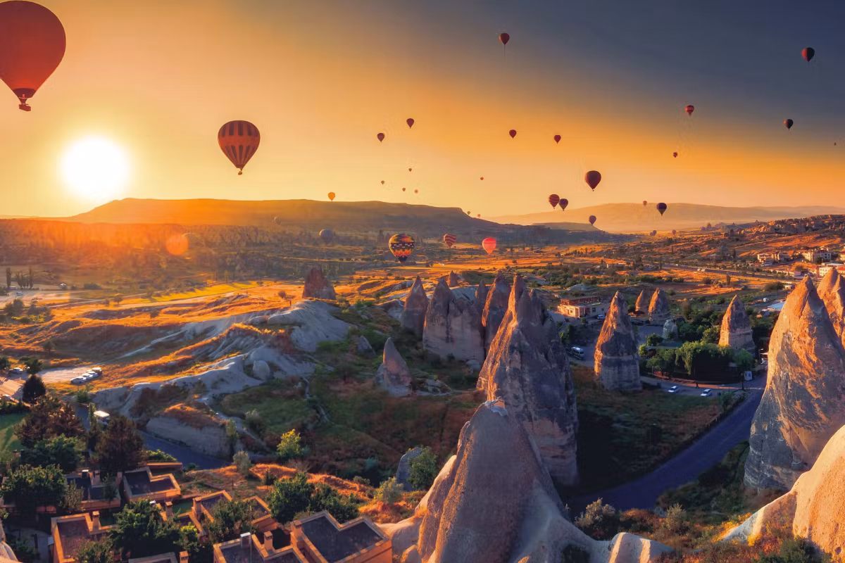 Low sun flaring over cones and houses, a line of envelopes silhouetted on the skyline, Cappadocia