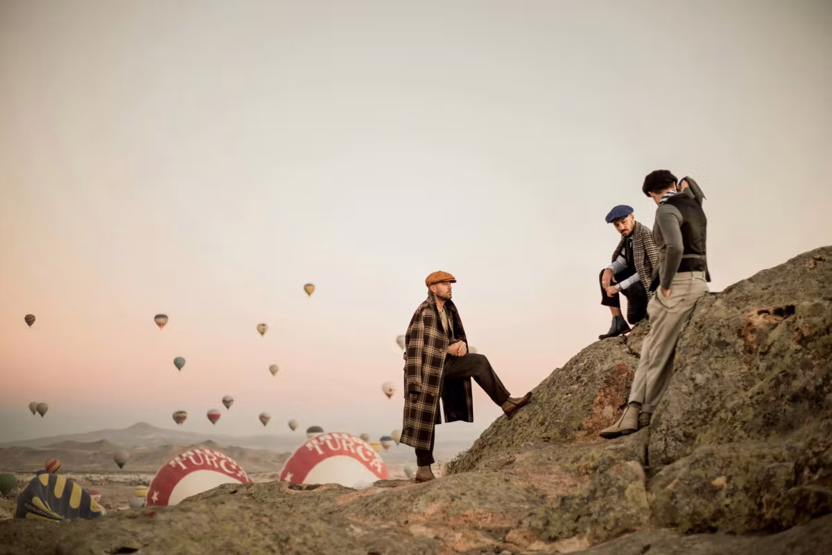 Models posed on an outcrop beside collapsing striped fabric, more envelopes far off, Cappadocia