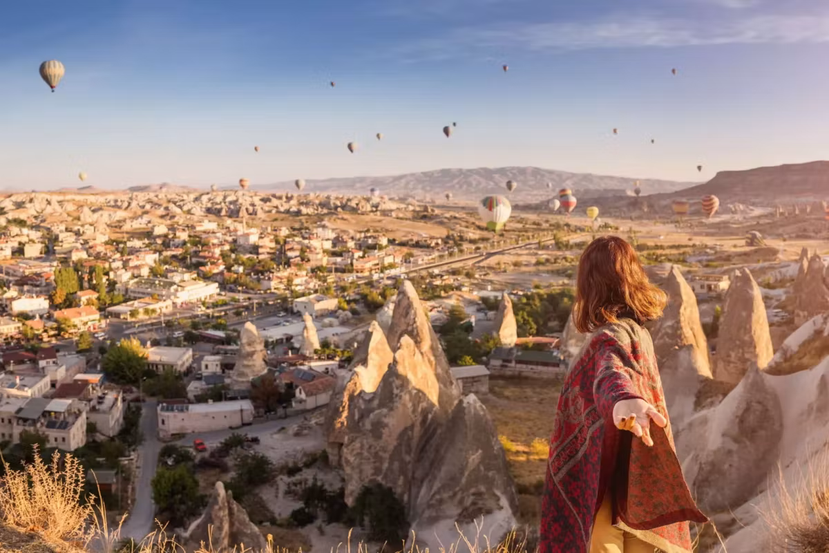 Woman in a printed wrap at a Goreme belvedere, the settlement and its tufa below
