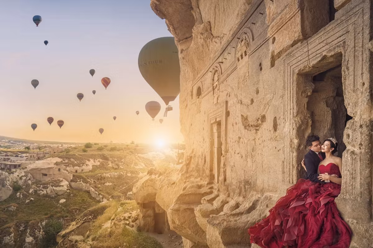 Scarlet gown leaning in at a cut rock front as the sun breaks over a valley full of envelopes, Cappadocia