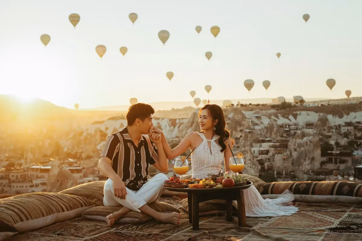 Low table set on a rug over bare rock as the sun comes up through a sky of envelopes, Cappadocia