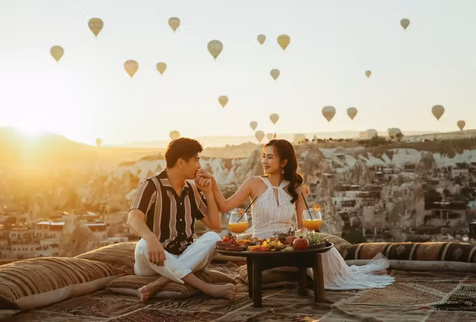 Low table set on a rug over bare rock as the sun comes up through a sky of envelopes, Cappadocia