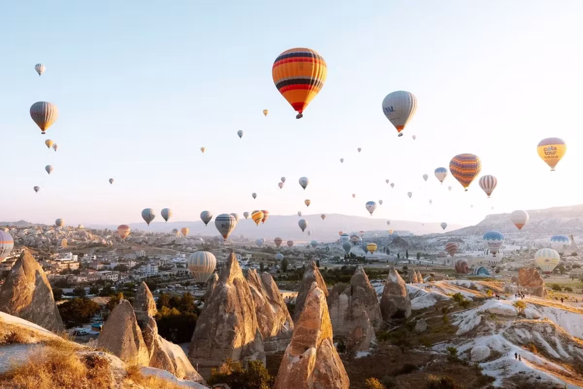 Vivid scarlet and gold fabric nearest the lens, the rest of the flight strung out behind, Cappadocia