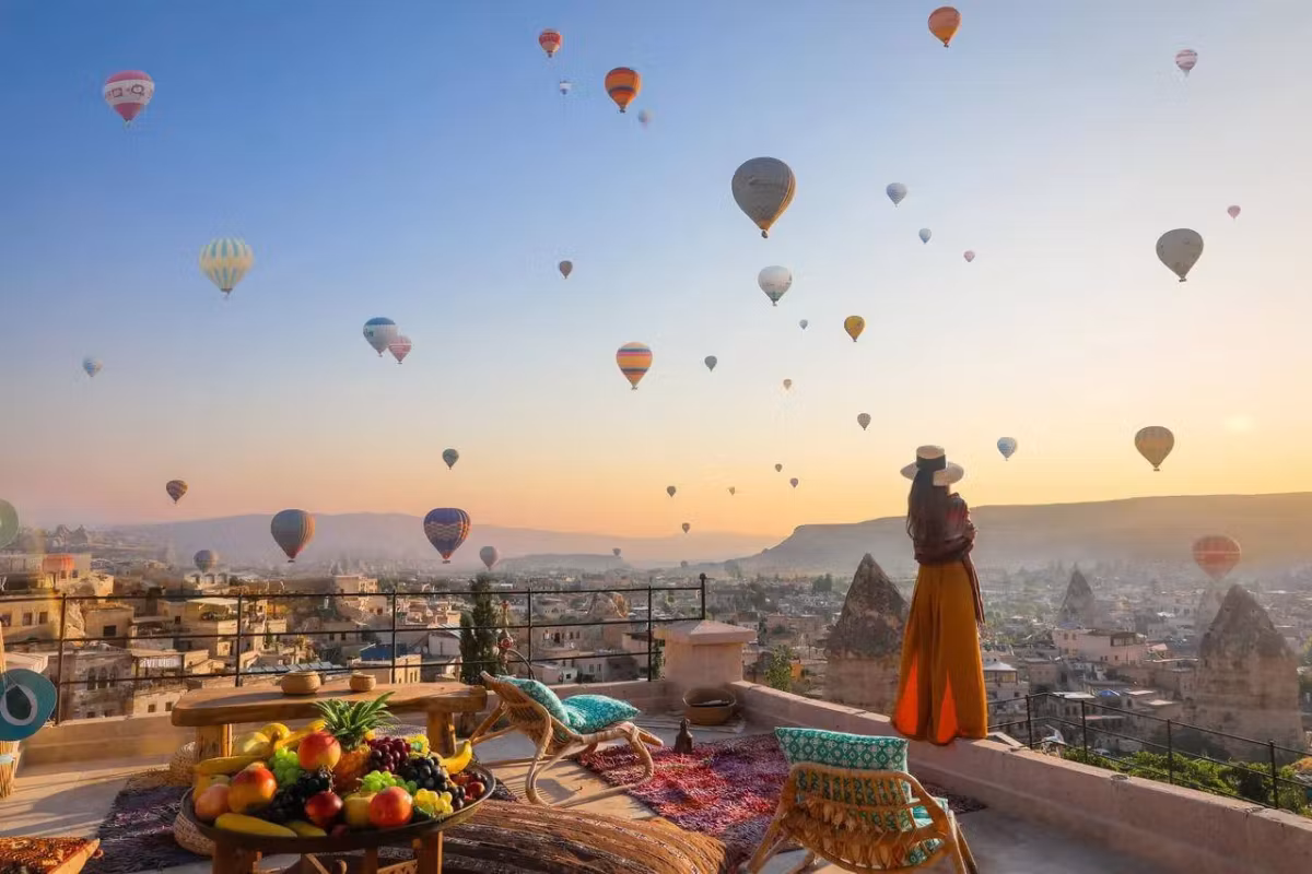 Fruit on a painted board, someone at the wall edge following the flight at daybreak, Cappadocia