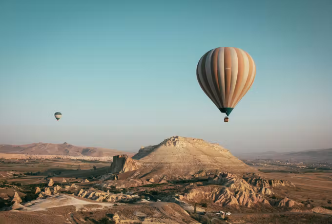 Lone envelope hanging over a flat-topped ridge with empty tableland under soft teal sky, Cappadocia