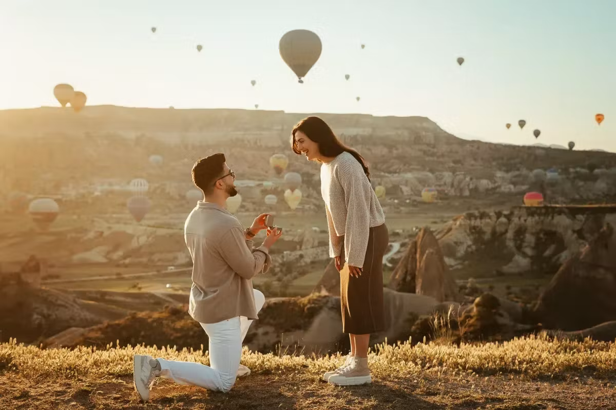 Kneeling on turf to ask the question at daybreak, colour drifting over the bowl behind, Cappadocia