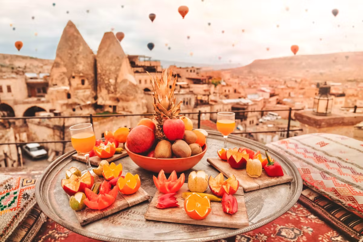 Juice and a fruit plate on a kilim-covered table, cones and envelopes filling the view, Cappadocia