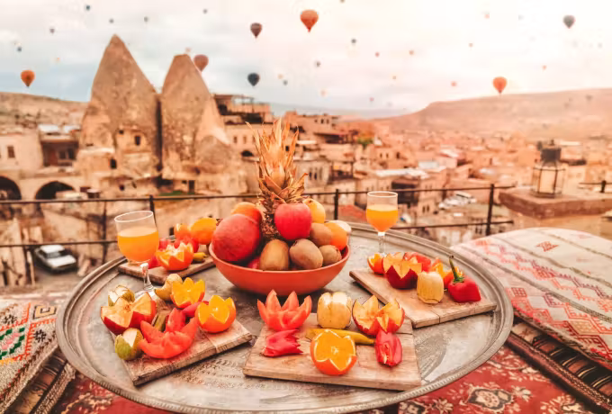 Juice and a fruit plate on a kilim-covered table, cones and envelopes filling the view, Cappadocia