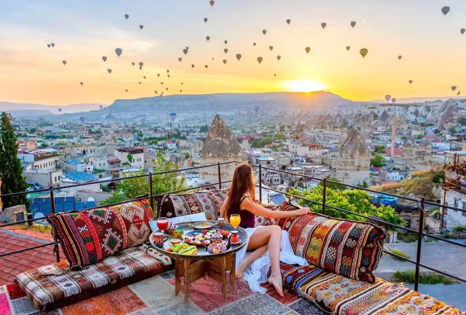 Terrace furnished with woven seats and a knee-high board as light reaches the settlement, Cappadocia