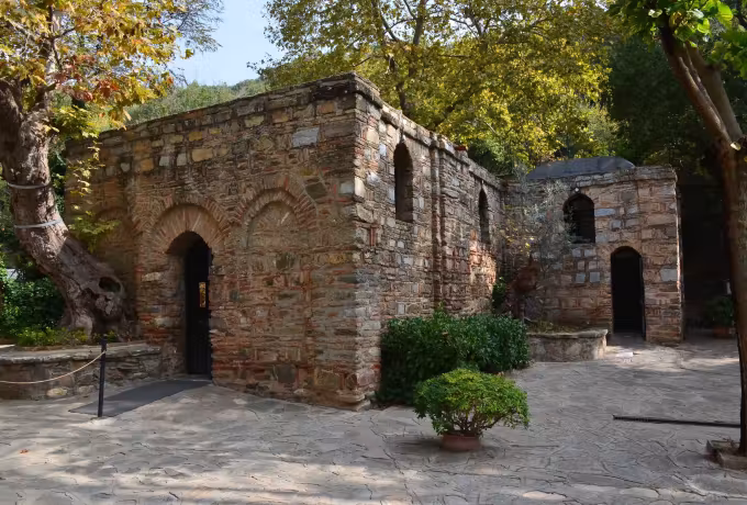 Quiet yard at Meryem Ana with the masonry chapel and its annex among trees turning gold