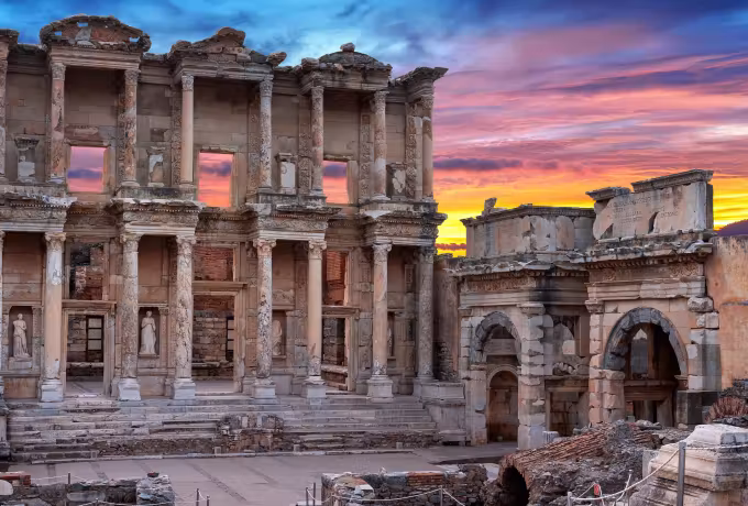 Fierce evening sky behind the Celsus front, its stonework burnished to deep gold, Ephesus