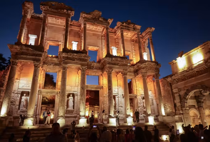 Night at Ephesus with the great elevation floodlit gold and people massed on the bright stair