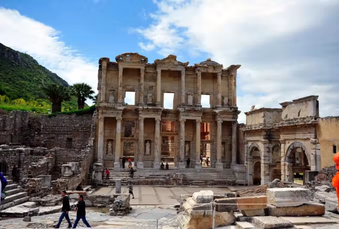 Vivid green slope above the Celsus front on an overcast spring day, people on the court, Ephesus