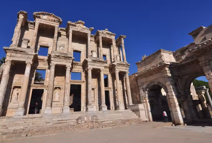 Taken from the paving, the Celsus front and Roman gate against deep clear blue, court empty