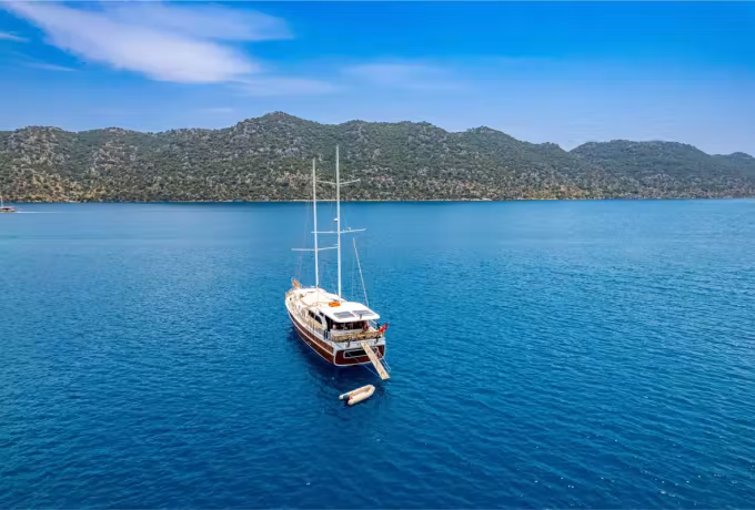 Low green hills around a sheltered Fethiye inlet with one boat riding alone on dark water