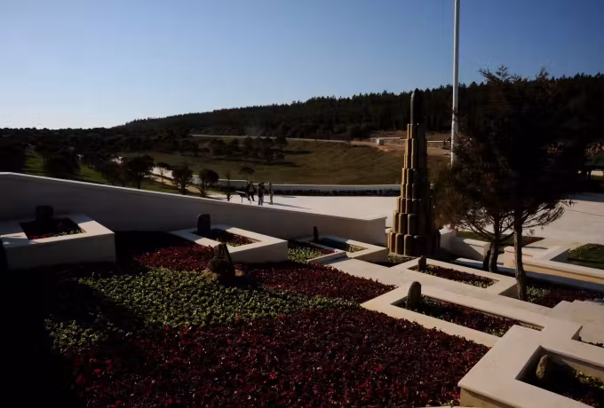 Low beds and dressed walling in a garden of remembrance, sea showing past the crest, Gallipoli