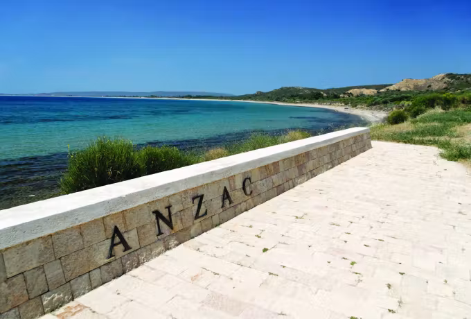 Masonry defence bearing the Anzac name, bending round the shingle at the landing place