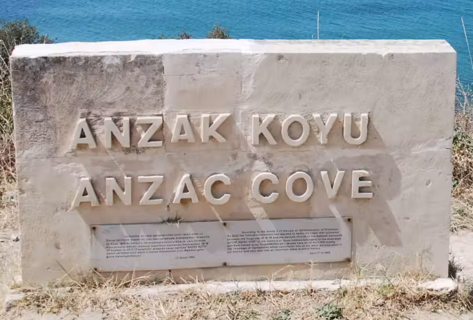 Place name given in two languages on a worked slab standing in parched turf above the beach, Gallipoli