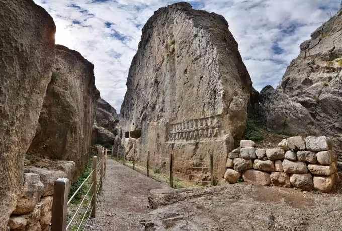 Handrailed way threading a split in the rock, a worked band on the flank to the right, Hattusa