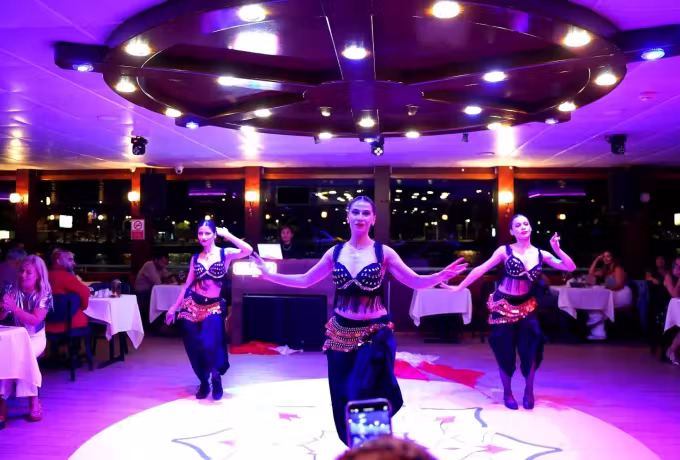 Beaded costumes moving as a trio on the circular lit stage of a Bosphorus cruise