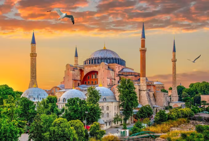 Gulls crossing a blazing orange evening behind the great cupola and its towers, Istanbul