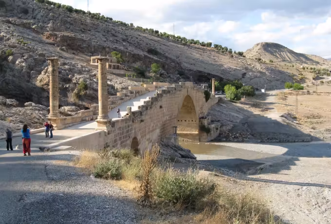 People walking up to the Cendere crossing, its surviving shafts at the head of the span