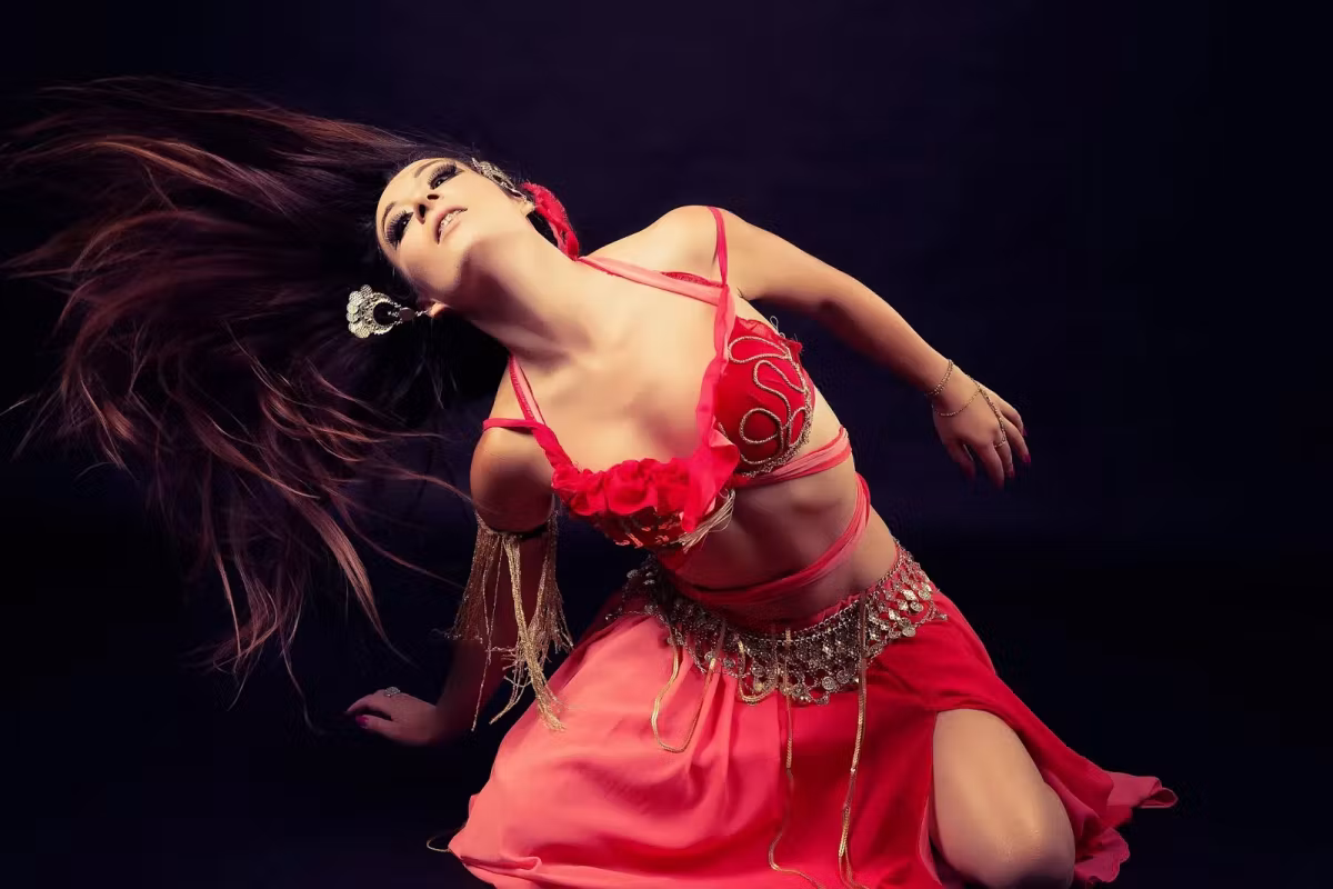 Pink and red costume dropping into a spin, hair thrown loose against the dark, Istanbul